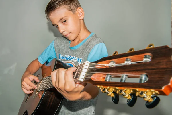 Pojke med en gitarr på en grå bakgrund i studion, vidvinkel foto. — Stockfoto