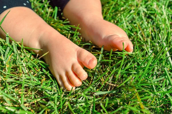 Маленький ребенок на траве, маленькие ноги на зеленой траве в р — стоковое фото