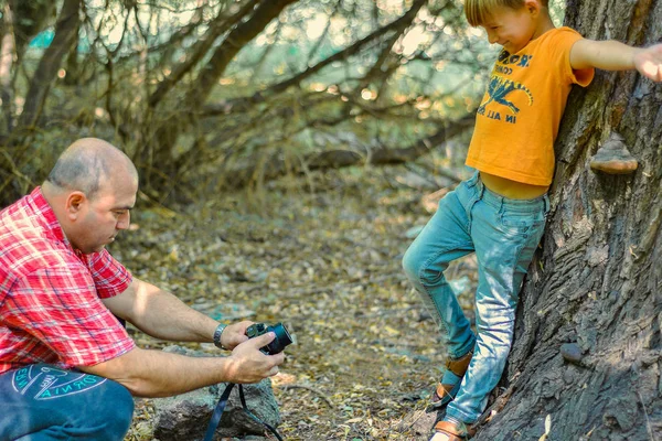 Bir adam ormanda bir çocuğun fotoğraflarını çekiyor. Doğayla savaşıyor. — Stok fotoğraf