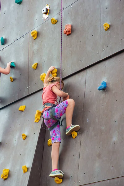 Dziewczyna skrada się na sztucznej wieży wspinaczkowej z ubezpieczeniem w ekstremalnym parku sportowym. — Zdjęcie stockowe