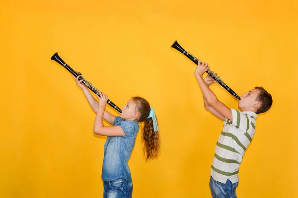 Chlapec a dívka hudebníci hrající na klarinet, na žlutém backgro — Stock fotografie