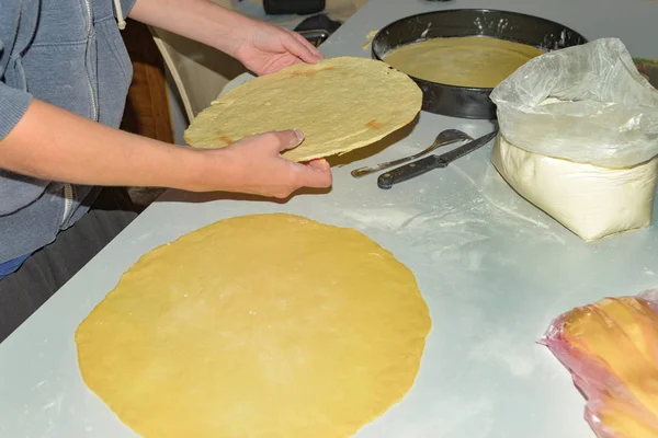 A woman rolls the dough for making pita bread in the oven.