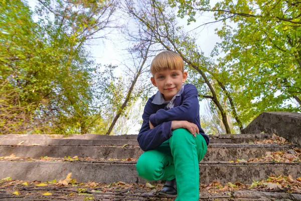 Terk edilmiş eski bir parkın merdivenlerinde bir çocuk oturuyor, aşağıdan manzaralı.. — Stok fotoğraf