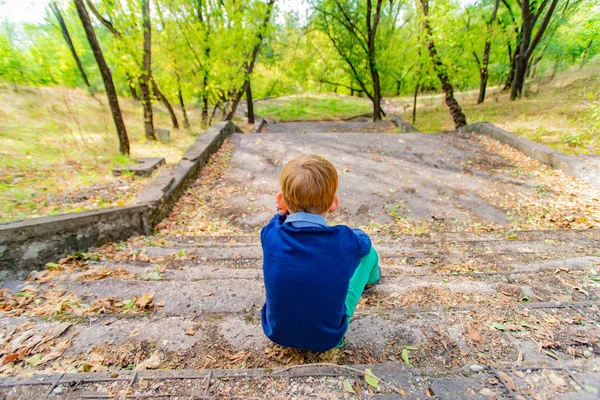 El chico se sienta en las escaleras y mira el descenso, la vista trasera . —  Fotos de Stock