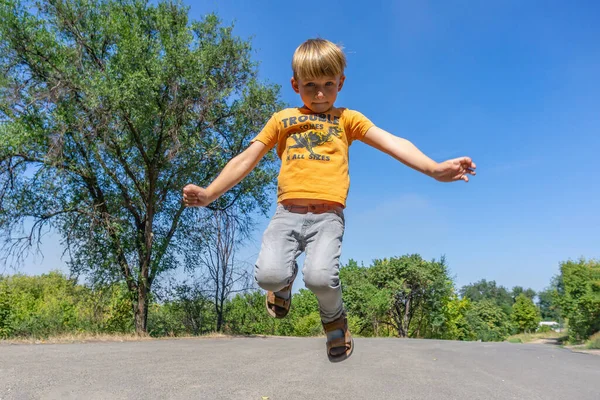 Radosny i szczęśliwy chłopiec skacze na drodze. — Zdjęcie stockowe