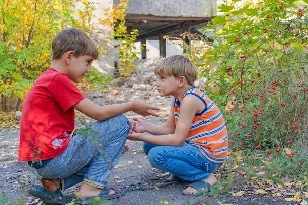 İki erkek çocuk parkta karşı karşıya oturur ve birbirleriyle iki kez iletişim kurarlar.. — Stok fotoğraf