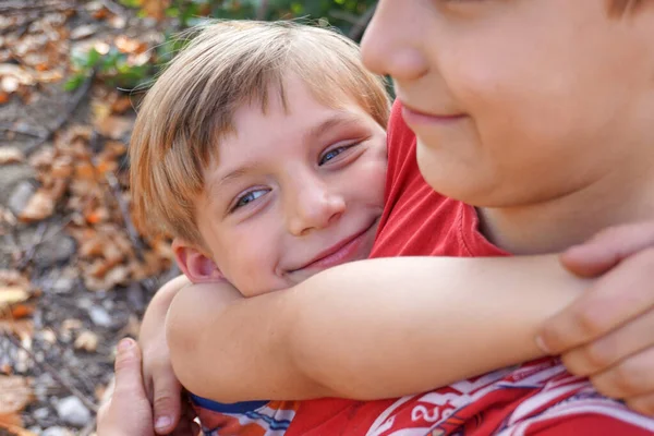 Chłopiec przytula swojego starszego brata, koncepcję dobrego samopoczucia rodziny i odpowiedniego wykształcenia. — Zdjęcie stockowe