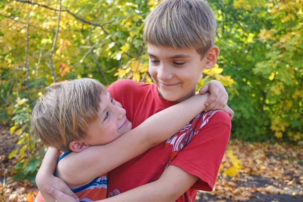 O irmão mais novo abraça o mais velho e olha para ele, dois lov — Fotografia de Stock