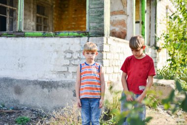 Two brothers are standing near a burned-out house, who lost thei clipart