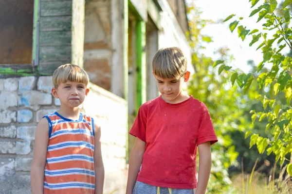 Dos hermanos están de pie cerca de una casa quemada, que perdió la suya. — Foto de Stock