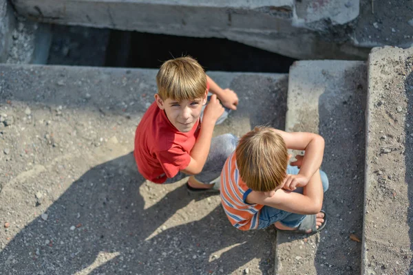 Duas crianças estão sentadas nos degraus de um edifício abandonado , — Fotografia de Stock
