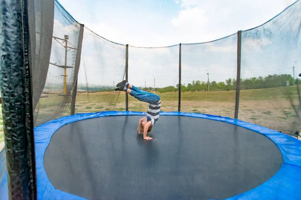 Boy does a somersault jumping on a trampoline in a sports extreme park. — Stock Photo, Image