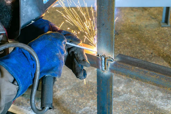 The welder makes a rack of metal corners and plates connecting them by electro-welding.