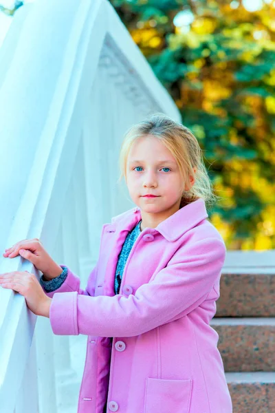 Teenager girl in a pink coat on the steps — Stock Photo, Image