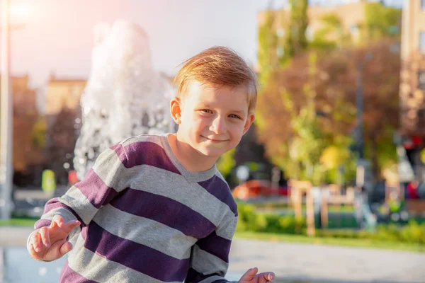 Bello e carino ragazzo sorride e posa sullo sfondo della fontana — Foto Stock
