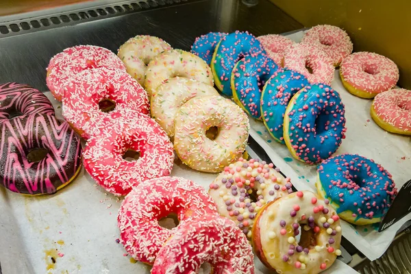 Colored donuts on a store counter, bakery sale. Tasty, sweet and beautiful buns