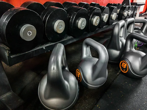 Dumbbells and weights for sports are on the rack and on the floor in the gym.