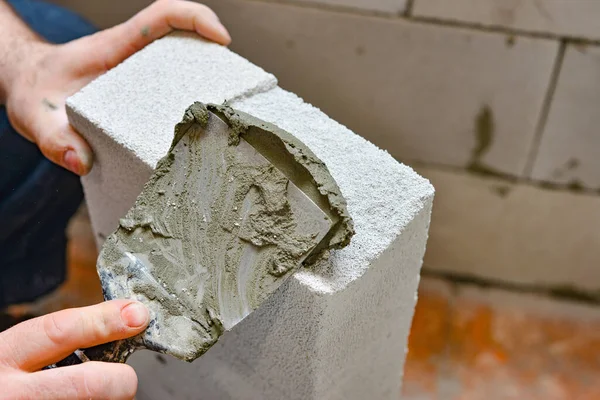 A worker applies adhesive mortar to a wall block in a private house. Foam masonry, repair and construction