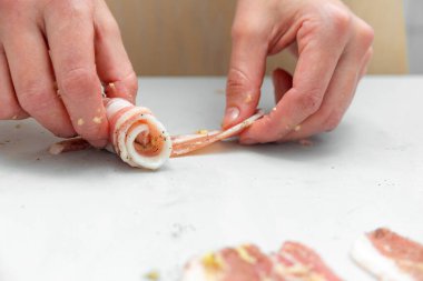 Kadın hostes daha fazla pişirmek ve tavada kızartmak için ince dilimlenmiş pastırmayı rulo haline getiriyor. Abur cubur pişirmek ve yağlı yiyecekler