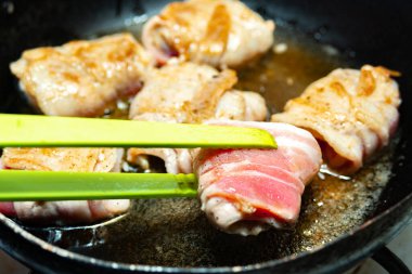 Garson tavada domuz pastırması ile kızarmış rulo çeviriyor. Abur cubur pişirmek ve yağlı yiyecekler