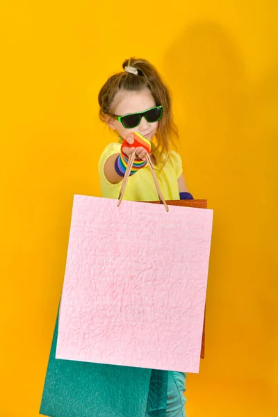 Ένα Κορίτσι Γυαλιά Στέκεται Πακέτα Και Ποζάρει Πορτοκαλί Φόντο — Φωτογραφία Αρχείου