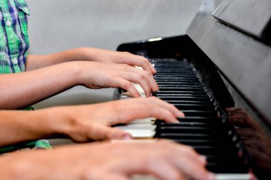 Erkek ve kız kardeş dört elle piyano çalar. Çocuklar müzik sanatını öğrenirler.