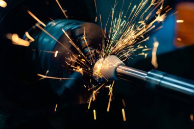 Dairesel öğütücüde aşındırıcı bir taşla çıkış deliğini öğütüyor.