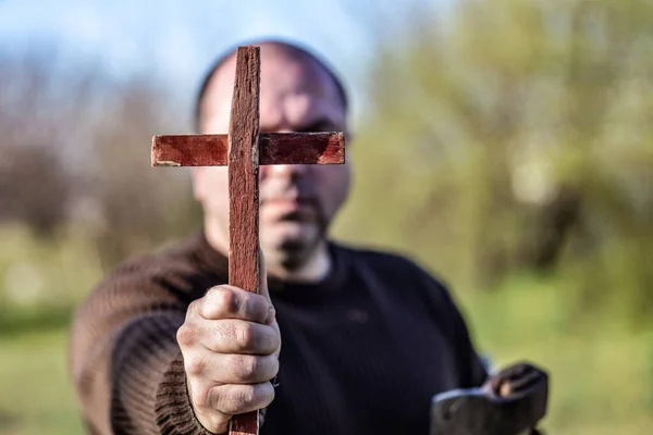男は目の前に木製のキリスト教の十字架 彼の一方で斧を保持しています ハロウィンで鬼を退治するというコンセプト — ストック写真