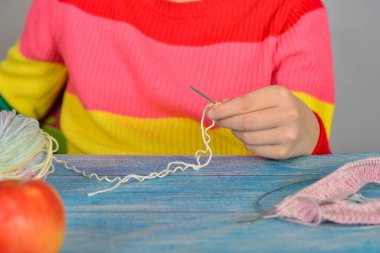 Elmalı bir masada oturan ve örgü örmeyi öğrenen bir kız..