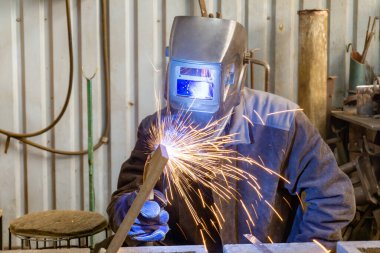 Bir elektromekanik atölyedeki elektrik ve gaz kaynakçısı mekanik bir montaj alanında metal bir yapı kaynaklıyor..