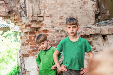 Two sad and unhappy brothers in a destroyed and abandoned building, staged photo.