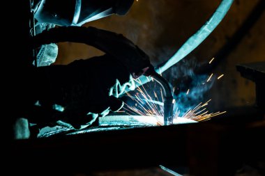 Elektrik ve gaz kaynakçısı bir kaynak şirketinin atölyesinde çalışıyor..