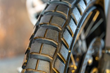 Motosiklet lastiğinin detaylı bir görüntüsü, su damlacıklarının ve dokuların renklendirildiği eşsiz lastik desenlerini ortaya çıkarır. Bu yakın çekim, tekerleğin dizaynını gösteriyor. Çekiş ve kavrama için gerekli..