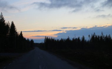 Kuzey İsveç'te açık renkli gün batımı ve karanlık manzara