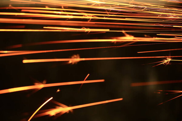 Spraying sparks from metalworking on a dark background.