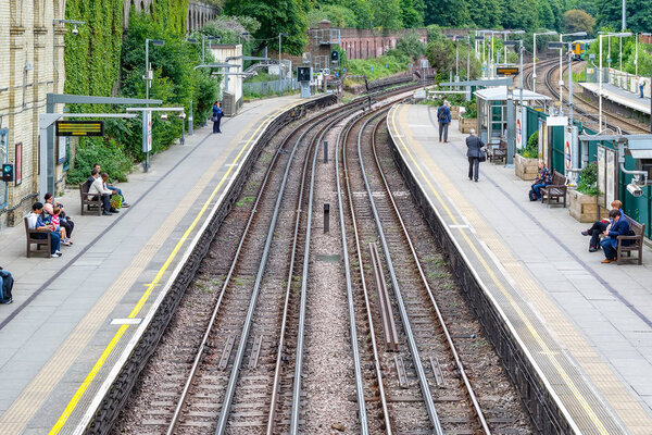 Лондон, Великобритания - 23 мая 2017 - West Brompton underground station platforms, with commuters waiting on platforms
