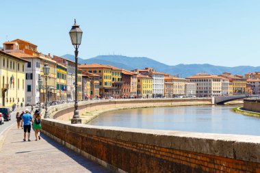 Turistler Pisa cityscape ile Arno Nehri boyunca yürüyüş 