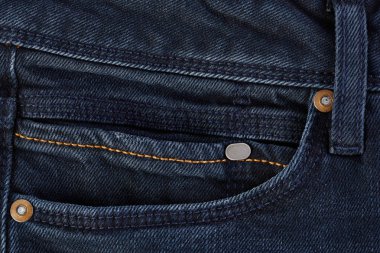 Denim kot desenli yırtık. Renkli pamuk kumaşın dokusu. Dikilmiş desenli kot pantolon. Moda pantolonu düğmesi. Kotun üzerindeki perçin ve cep. İplik ve kumaş yapısı.