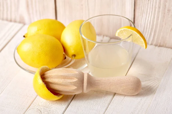 Freshly squeezed lemon juice. A glass of squeezed lemon juice and lemons around. Vitamins. Citrus fruits. Yellow.