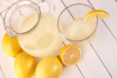 Taze sıkılmış limon suyu. Bir bardak sıkılmış limon suyu ve limon çevresinde. Vitaminler. Narenciye meyve. Sarı.