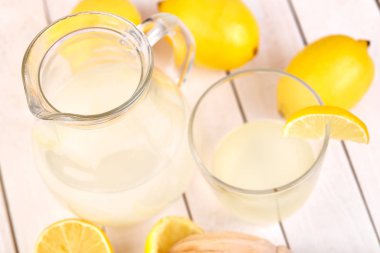 Taze sıkılmış limon suyu. Bir bardak sıkılmış limon suyu ve limon çevresinde. Vitaminler. Narenciye meyve. Sarı.