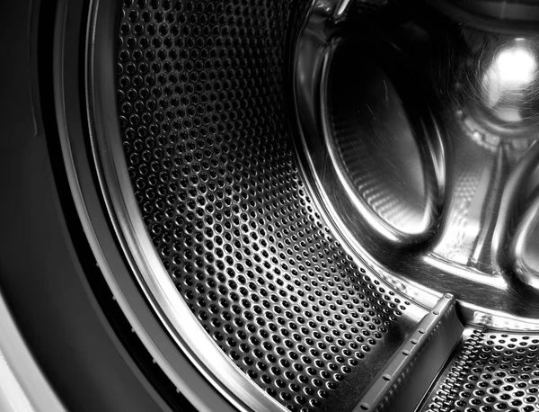 Washing machine drum interior. Perforated stainless steel drum for automatic washing machine. Black and white, metallic background