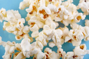 Parlak mavi bir arka plan üzerinde patlamış mısır. Film. Fast food. Mısır