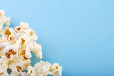 Parlak mavi bir arka plan üzerinde patlamış mısır. Film. Fast food. Mısır