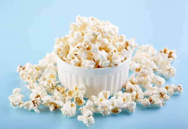 Popcorn on a bright blue background. Film. Fast food. Corn