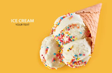 Dondurma topları renkli şeker sprinkles bir gözleme koni üzerinde sarı bir arka plan ile. Vanilyalı dondurma waffle koni.