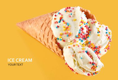 Dondurma topları renkli şeker sprinkles bir gözleme koni üzerinde sarı bir arka plan ile. Vanilyalı dondurma waffle koni.