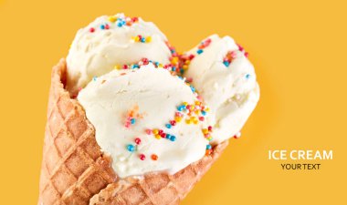 Dondurma topları renkli şeker sprinkles bir gözleme koni üzerinde sarı bir arka plan ile. Vanilyalı dondurma waffle koni.