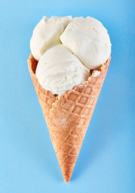 Mavi bir arka plan üzerinde bir gözleme külah dondurma topları. Vanilyalı dondurma waffle koni.