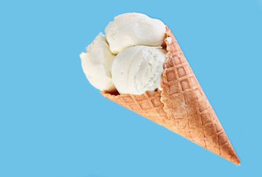 Dondurma topları renkli şeker sprinkles bir gözleme koni üzerinde mavi bir arka plan ile. Vanilyalı dondurma waffle koni.